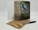 Greeting card with a bird design on a textured background, accompanied by an envelope and pen.