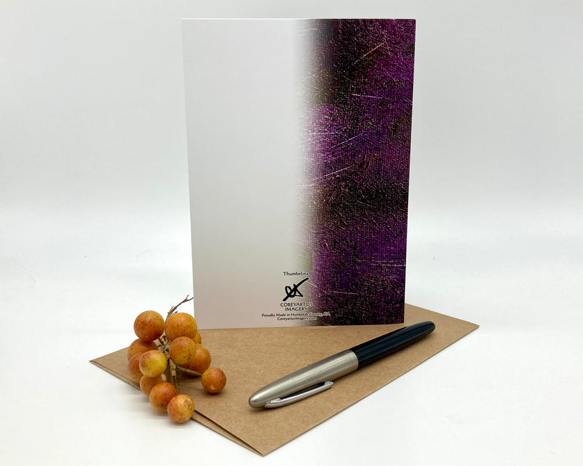 Greeting card with a purple design, pen, and fruit on a white background