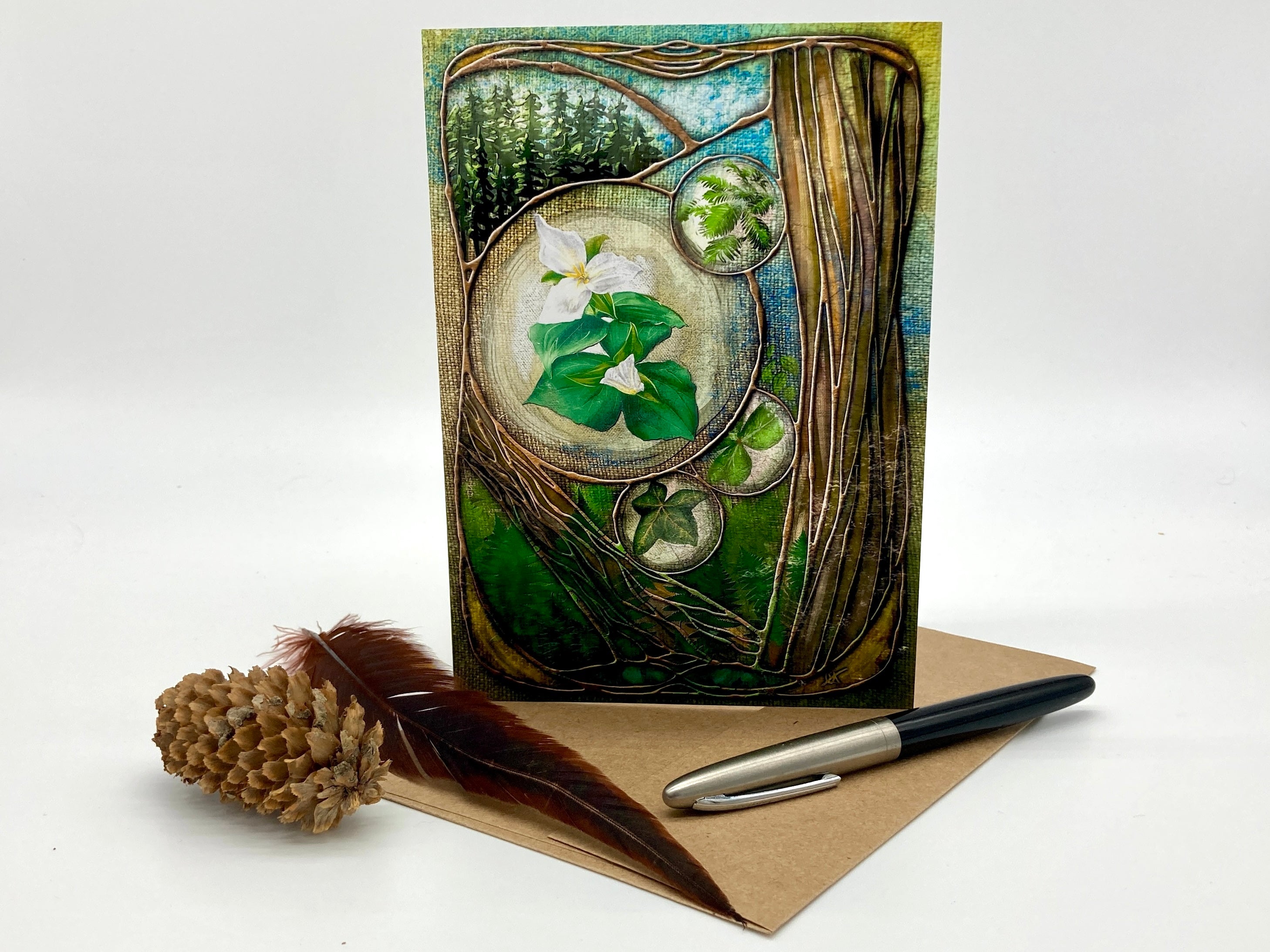 Greeting card with nature-themed design, pen, and pine cone on a white background