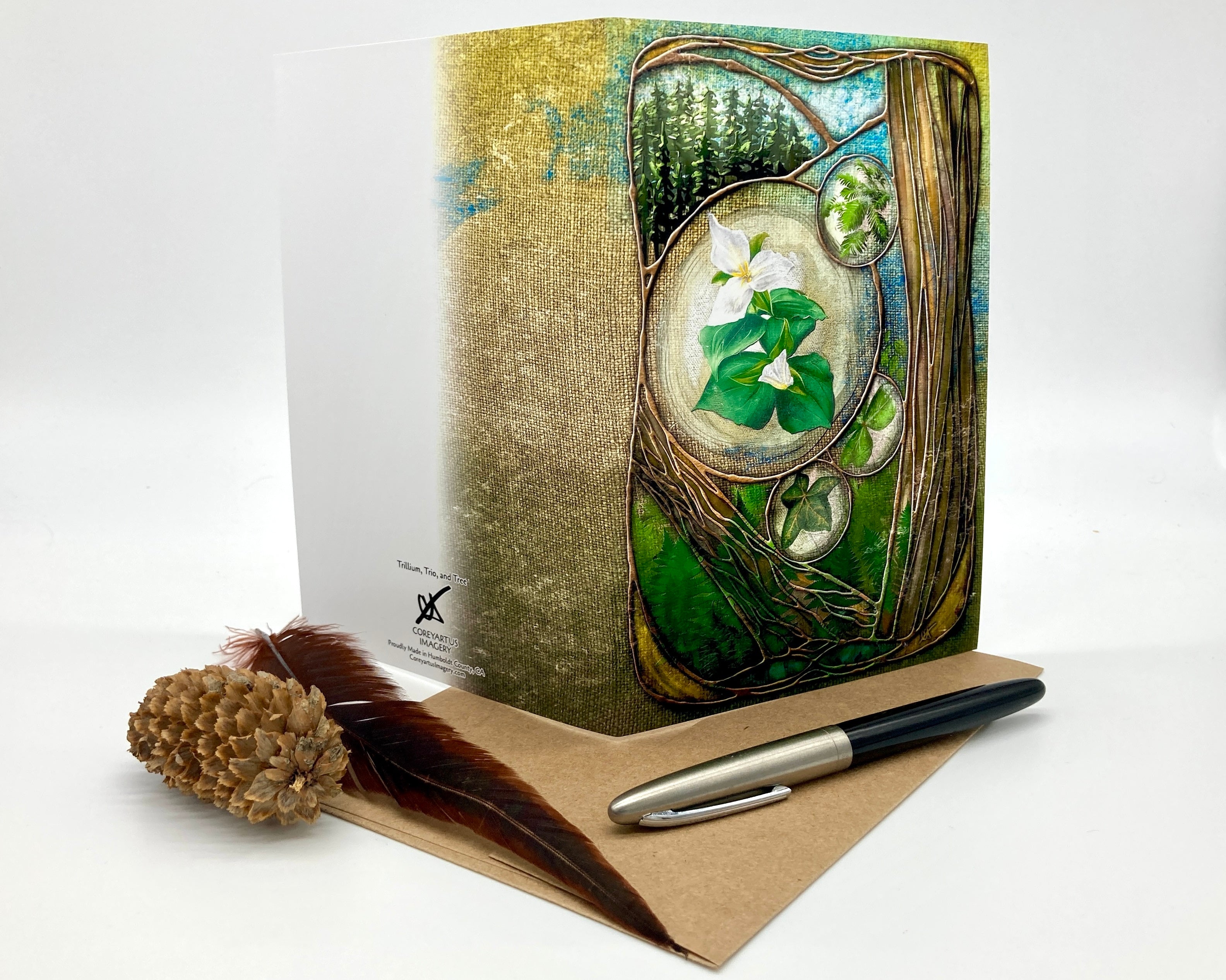 Decorative notebook with nature-themed cover, pen, and feather on a white background