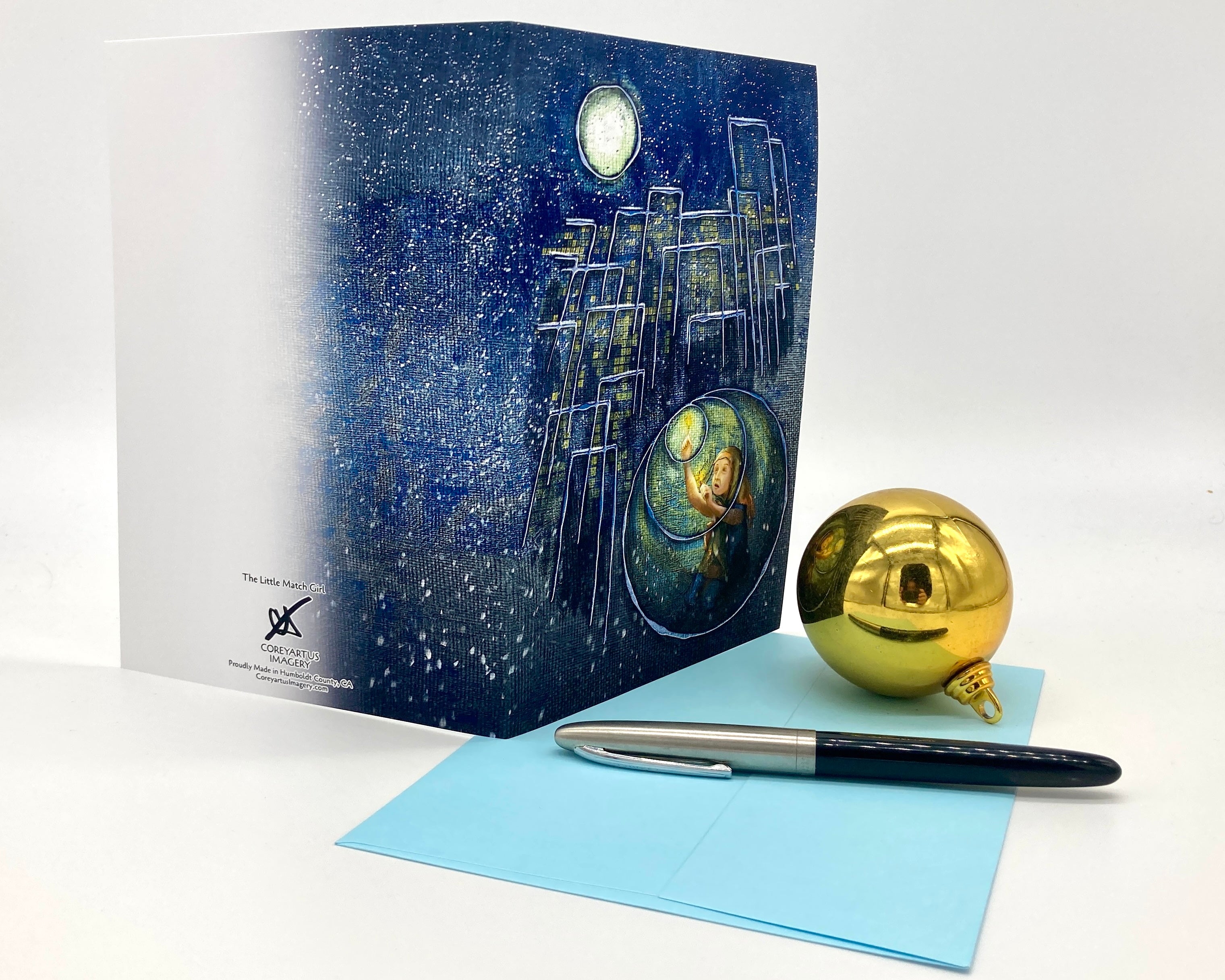 Greeting card with space-themed design, pen, and gold ornament on a white background
