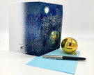 Greeting card with space-themed design, pen, and gold ornament on a white background