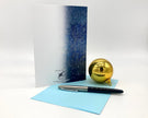 Gold ornament, pen, and card on a white background