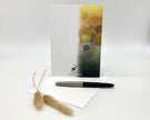Greeting card with abstract design, pen, and decorative item on a white background