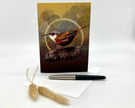 Greeting card with a bird design on a white background with a pen and decorative item.