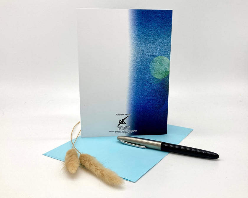 Greeting card with blue gradient design, pen, and decorative item on a white background