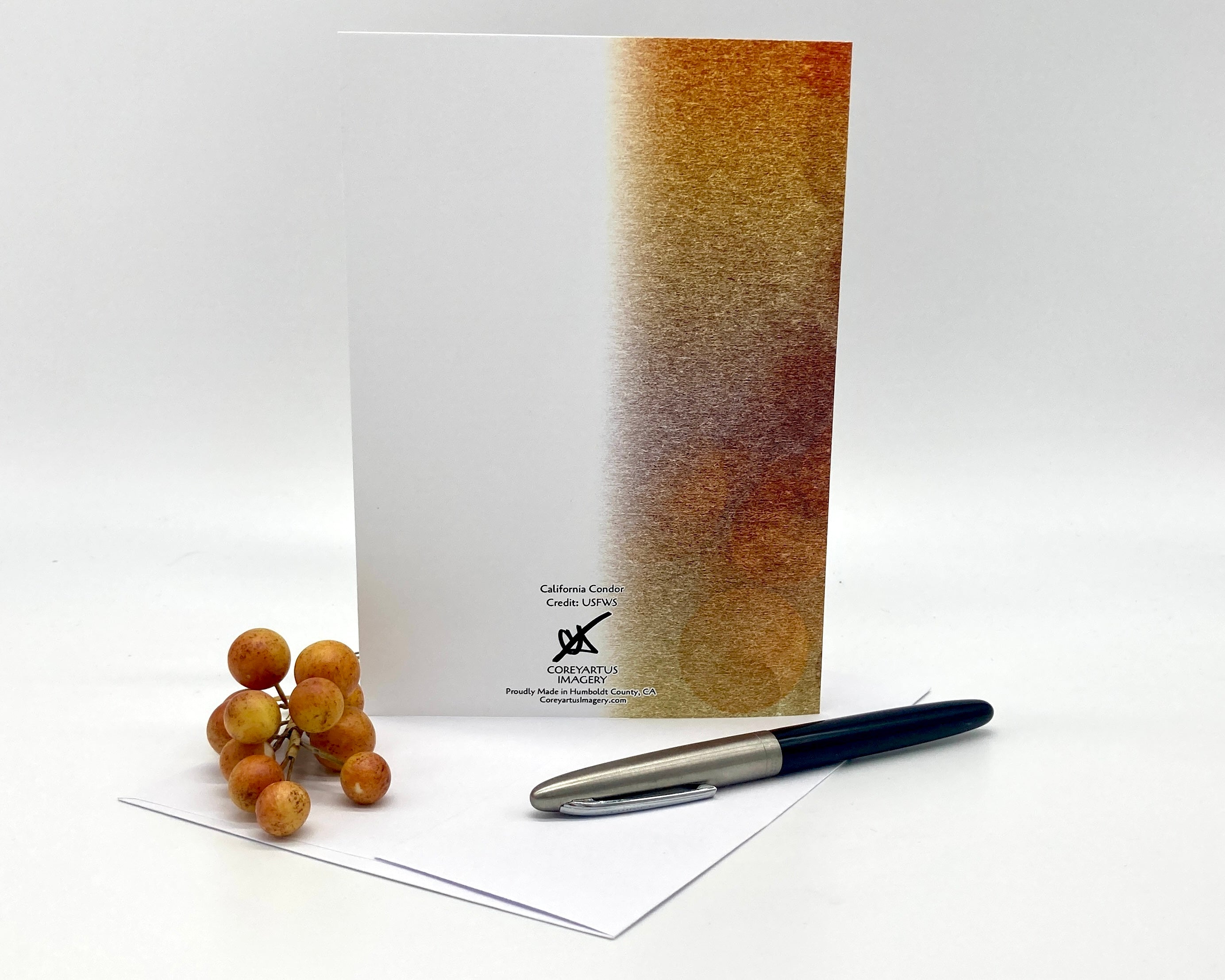 Greeting card with a gradient cover, grapes, and a pen on a white background