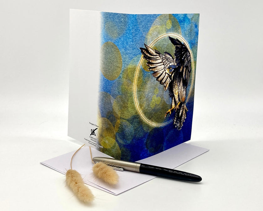 Greeting card with an eagle design on a blue and green abstract background, accompanied by a pen and brush.