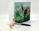 Greeting card with a bird design on a white surface with a pen and small object.