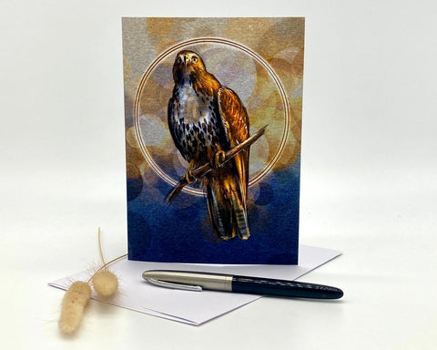 Greeting card with a hawk illustration on a blue background, accompanied by an envelope and pen.