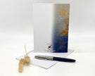 Greeting card with artistic design, pen, and decorative item on a white background