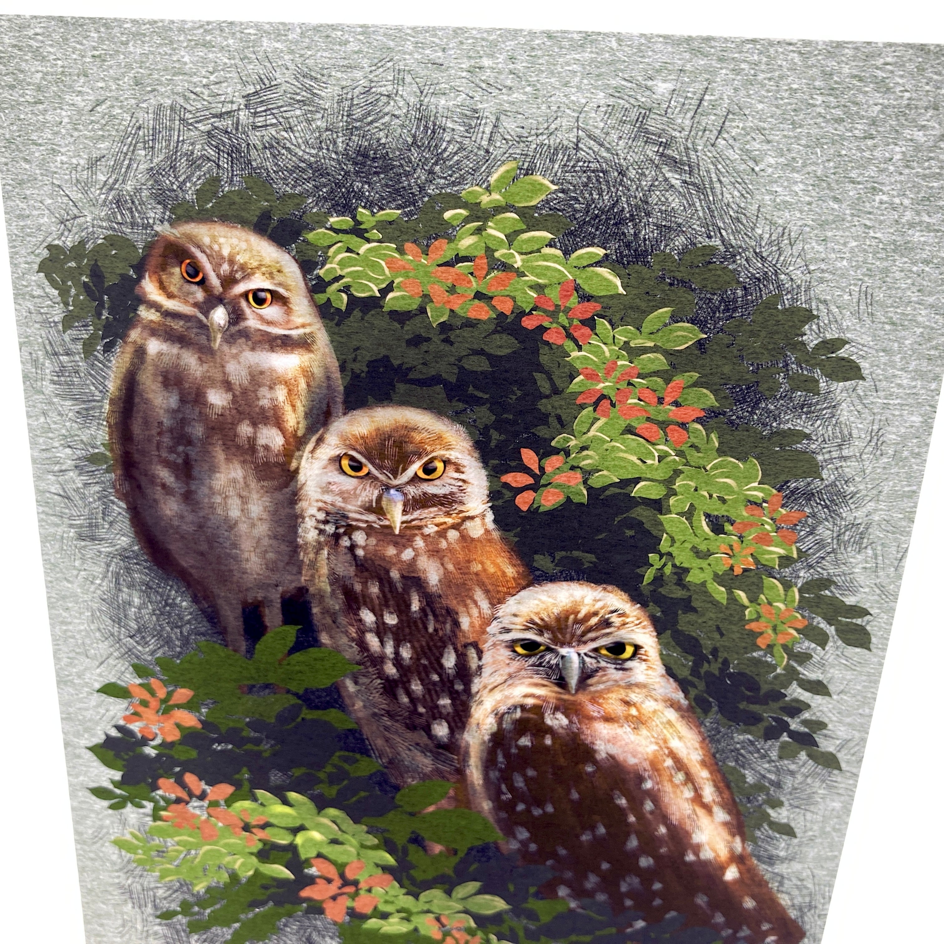 Three owls sitting together with greenery and flowers on a textured background