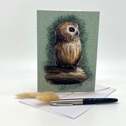 Greeting card with an owl illustration on a green background, accompanied by a pen and decorative straw.
