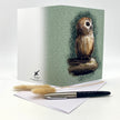 Greeting card with owl illustration on a white surface with a pen and envelope.