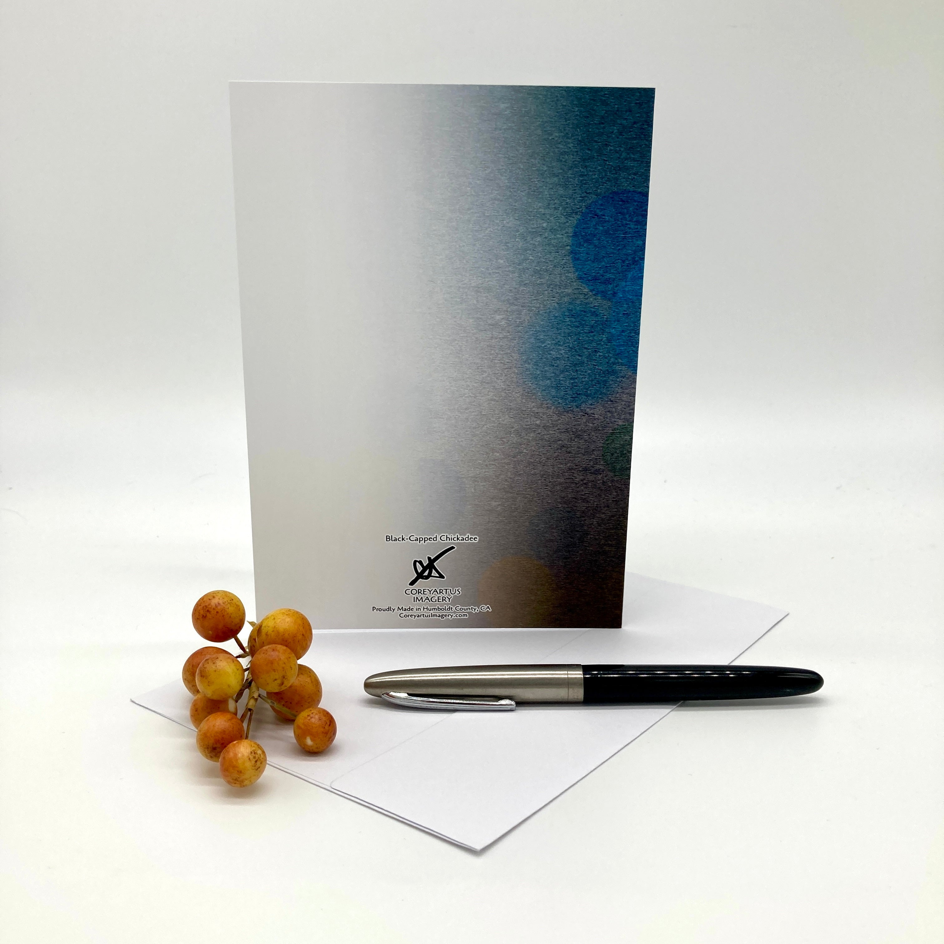 Backside of a greeting card with a pen and small fruit on a white surface