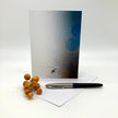 Backside of a greeting card with a pen and small fruit on a white surface