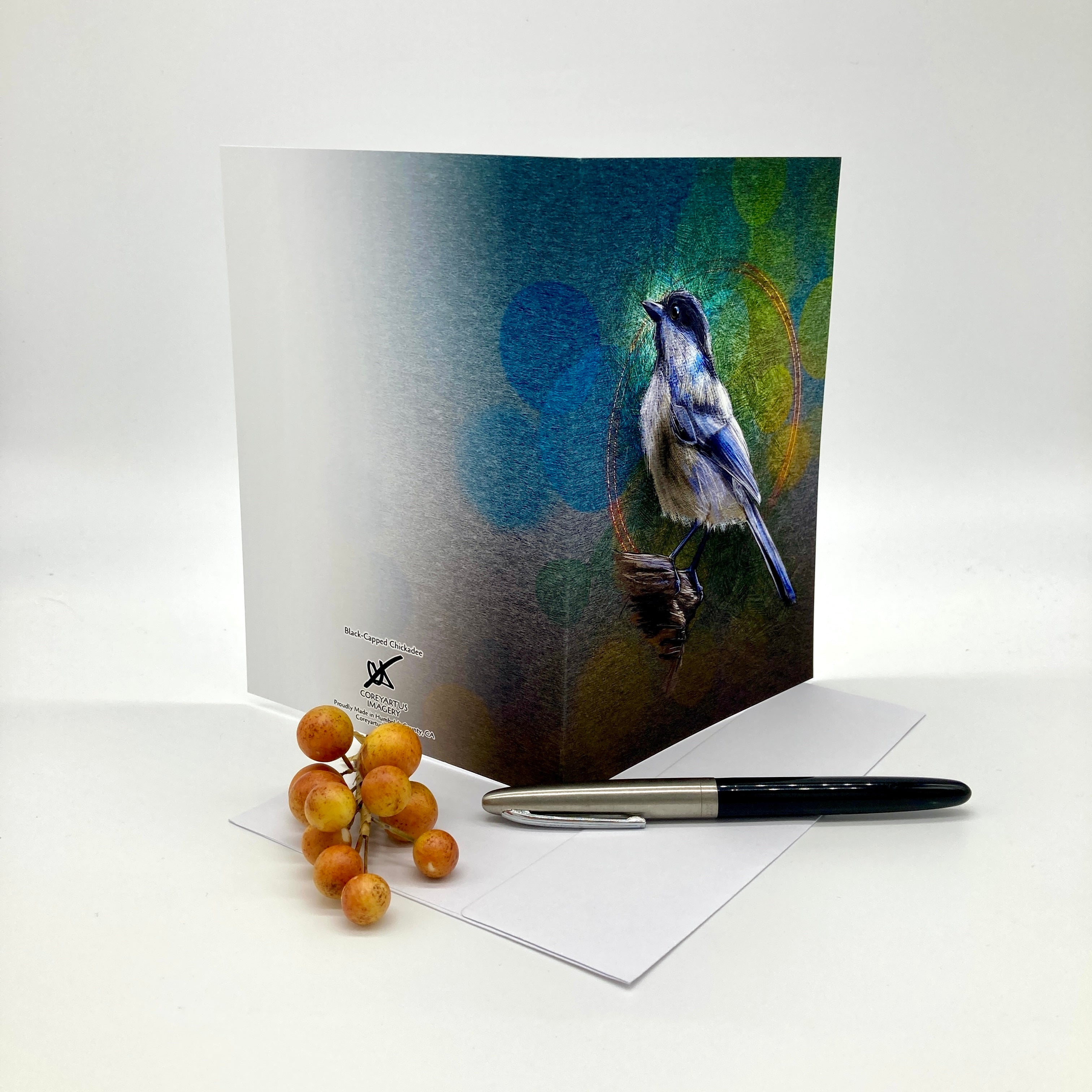 Greeting card with a bird design on a white surface with a pen and berries.