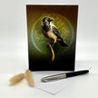 Greeting card with a bird design on a white surface with a pen and decorative item.