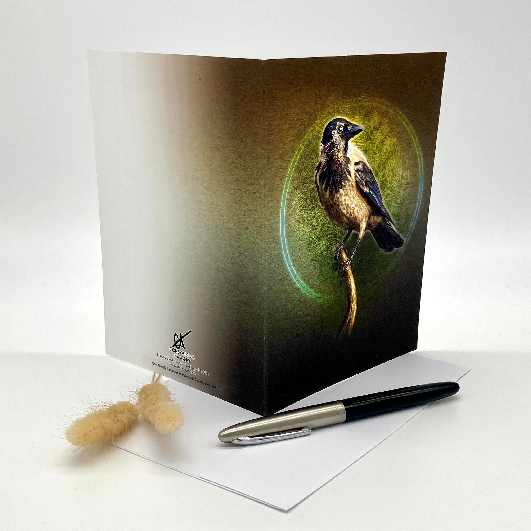 Greeting card with a bird design on a white surface with a pen and small object.