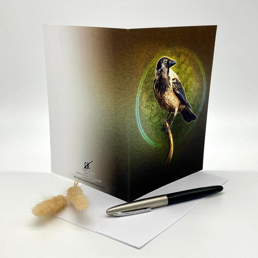 Greeting card with a bird design on a white surface with a pen and small object.