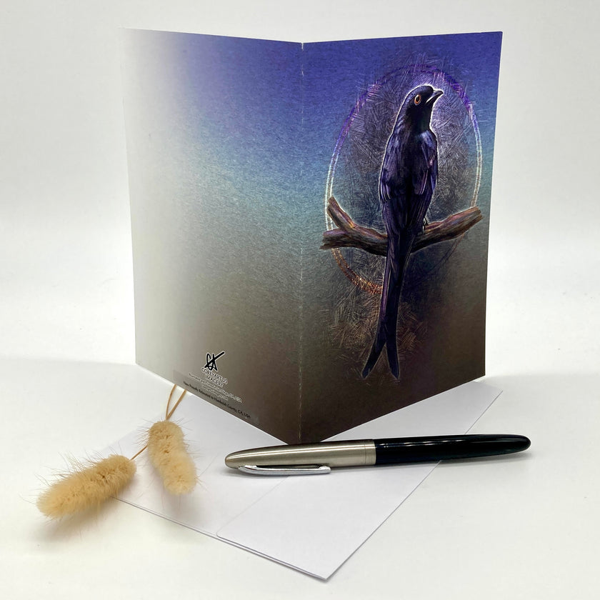 Greeting card with a bird design on a white surface with a pen and decorative item.