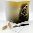 Greeting card with a bird design on a white surface with a pen and decorative item.