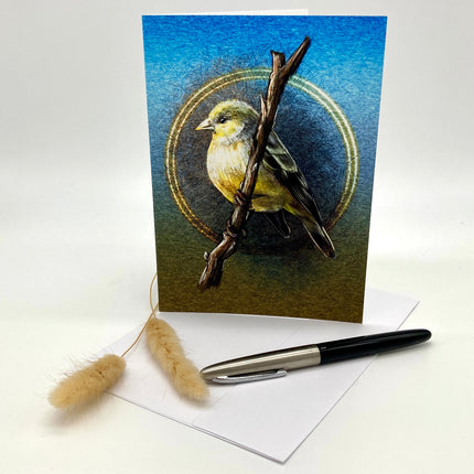 Greeting card with a bird illustration on a branch, placed on a white surface with a pen and decorative elements.