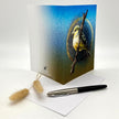 Greeting card with bird design on a white surface with a pen and decorative item.