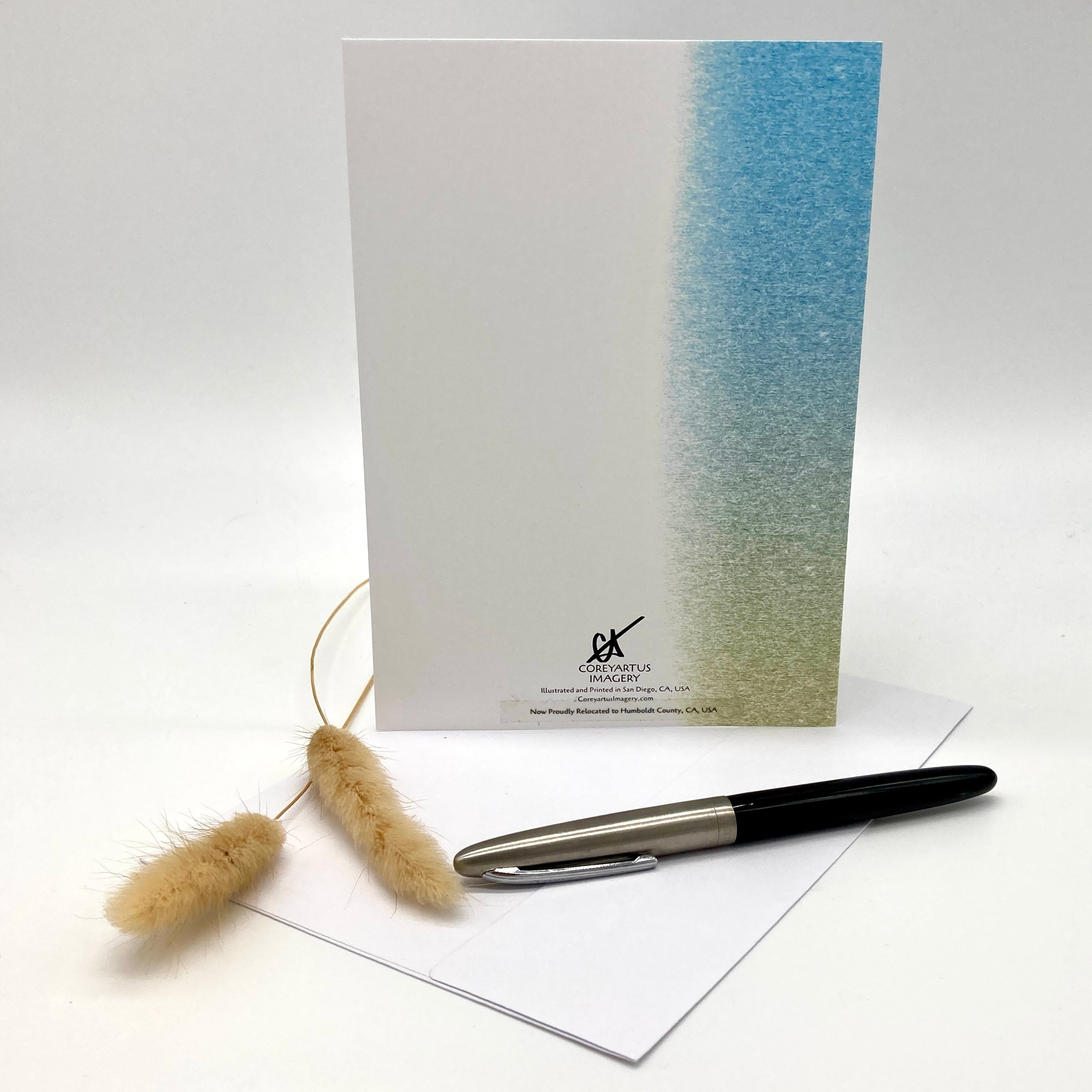 Greeting card with gradient design, pen, and cleaning brush on a white background