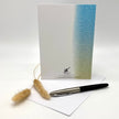 Greeting card with gradient design, pen, and cleaning brush on a white background