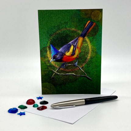 Greeting card with a colorful bird illustration on a green background, accompanied by a pen and decorative stones.