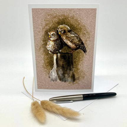 Product photo of a bird greeting card in brown featuring two burrowing pygmy owls on a stump.