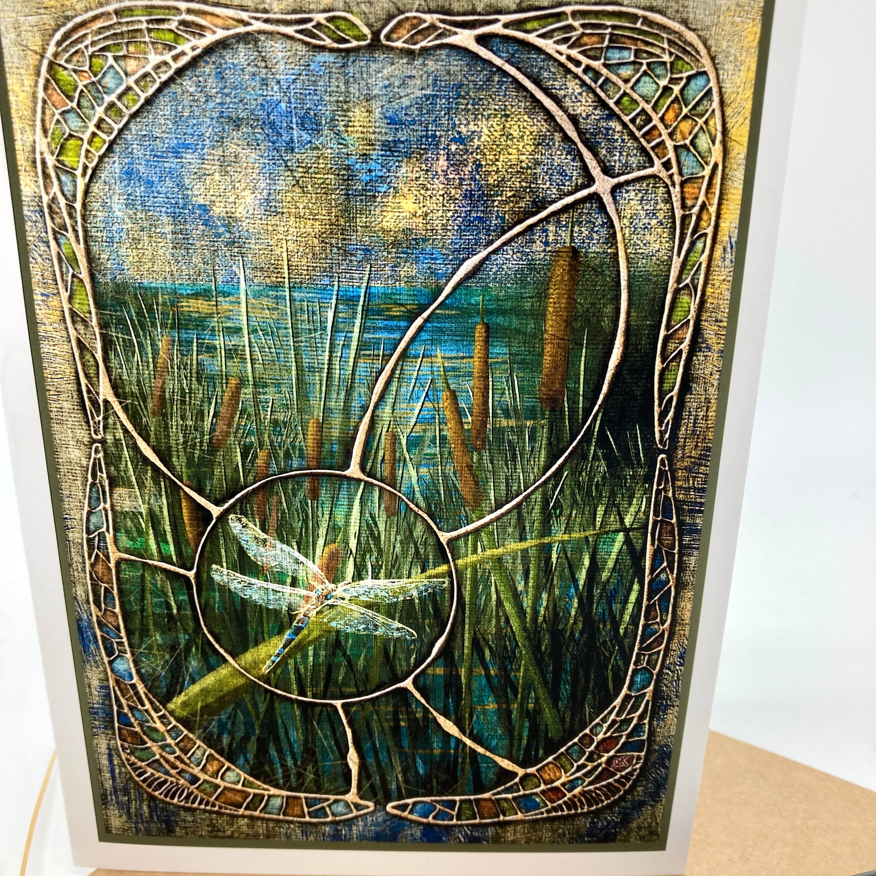 Closeup of greeting card featuring art nouveau styling around a dragonfly. Dominant colors are tans, greens, and browns.