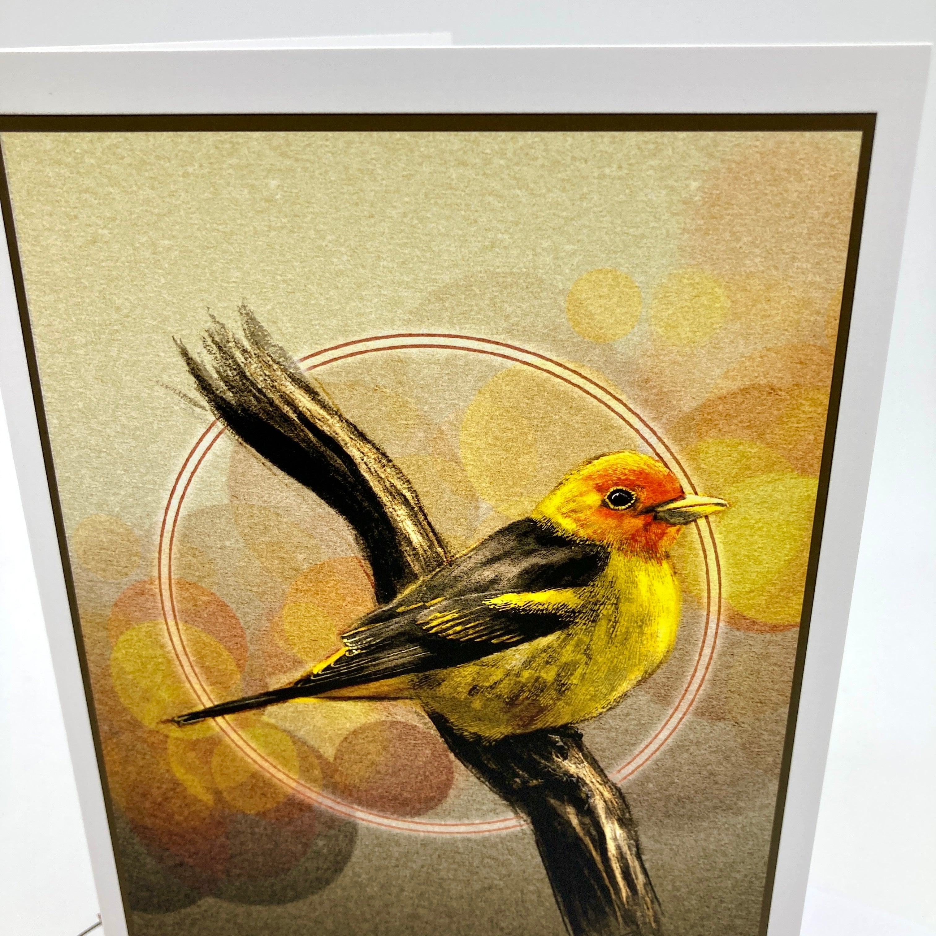 A framed art print featuring a detailed illustration of a yellow and orange bird perched on a branch against a textured beige background with soft circular bokeh-like shapes.