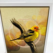 A framed art print featuring a detailed illustration of a yellow and orange bird perched on a branch against a textured beige background with soft circular bokeh-like shapes.