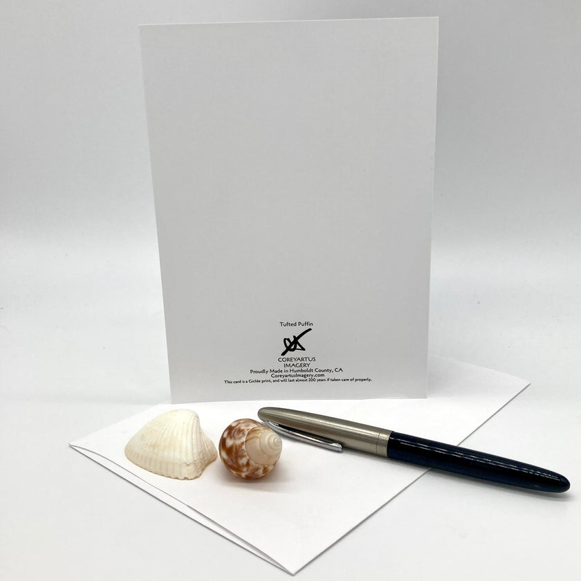 A white greeting card set with a matching envelope, pen, and two seashells on a light gray background. The card features a black printed logo and text for 'Tubular Pockets' at 'Pleasant Valley Glassworks, California'.