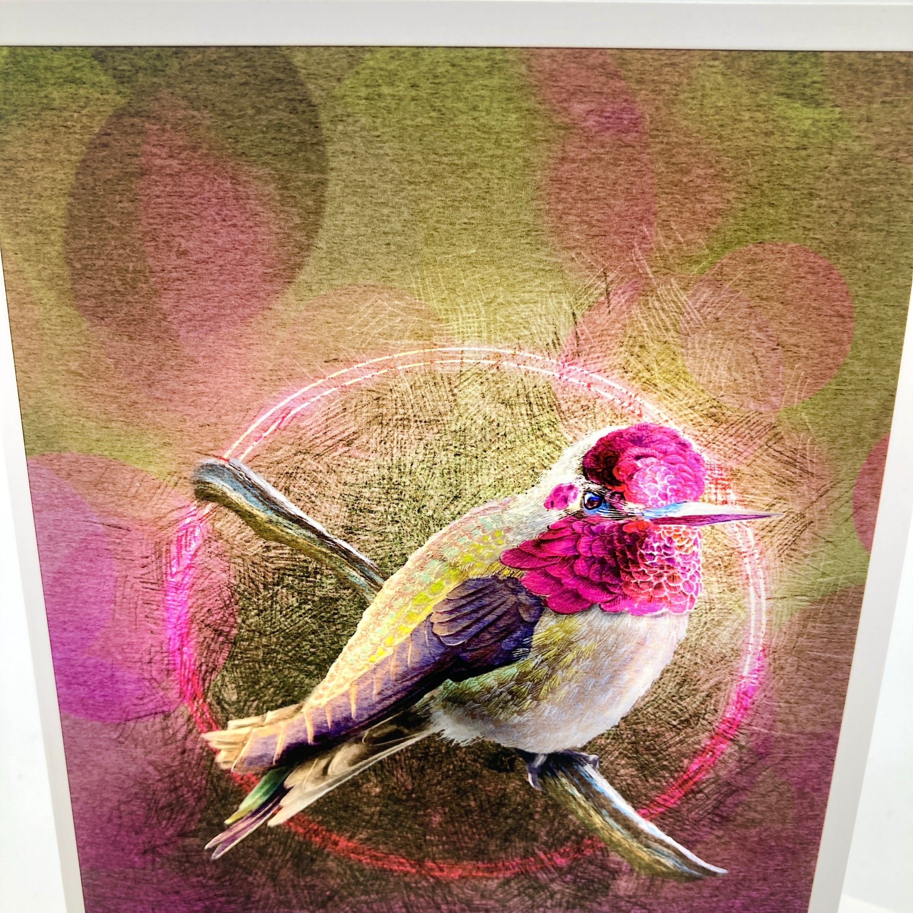 A art print greeting card featuring a hummingbird perched on branches with a glowing circular motif and pink-toned background.