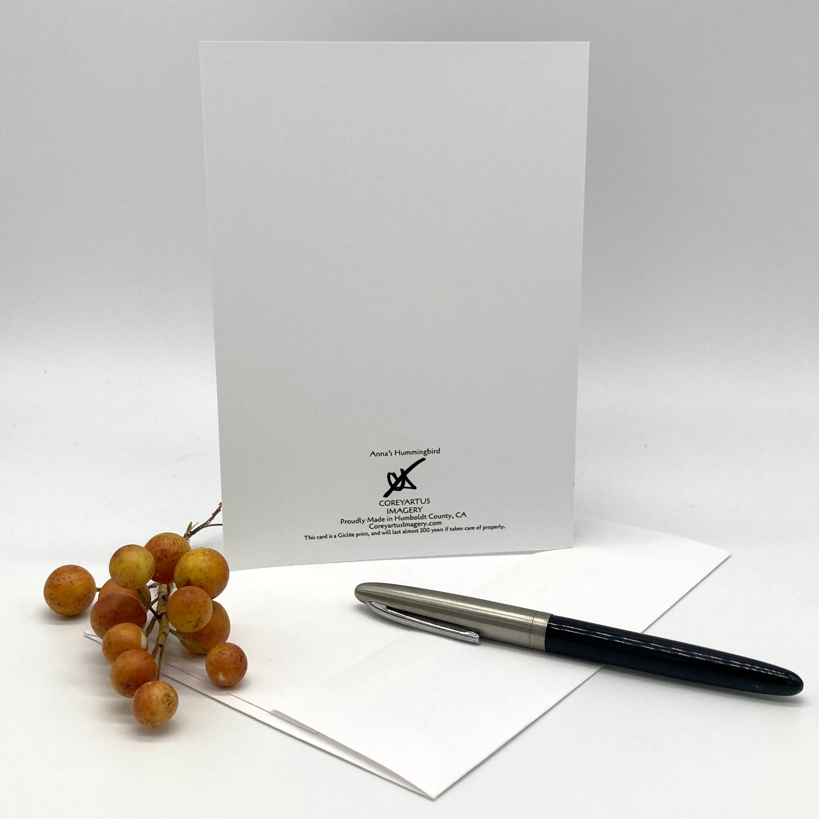 Back side of an art print greeting card white envelope and a black pen nearby.