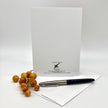A white stationery set featuring a letterhead card from the California Grapevine Winery, a matching white envelope, and a black and silver pen, styled with a small bunch of grapefruits on a light gray background.
