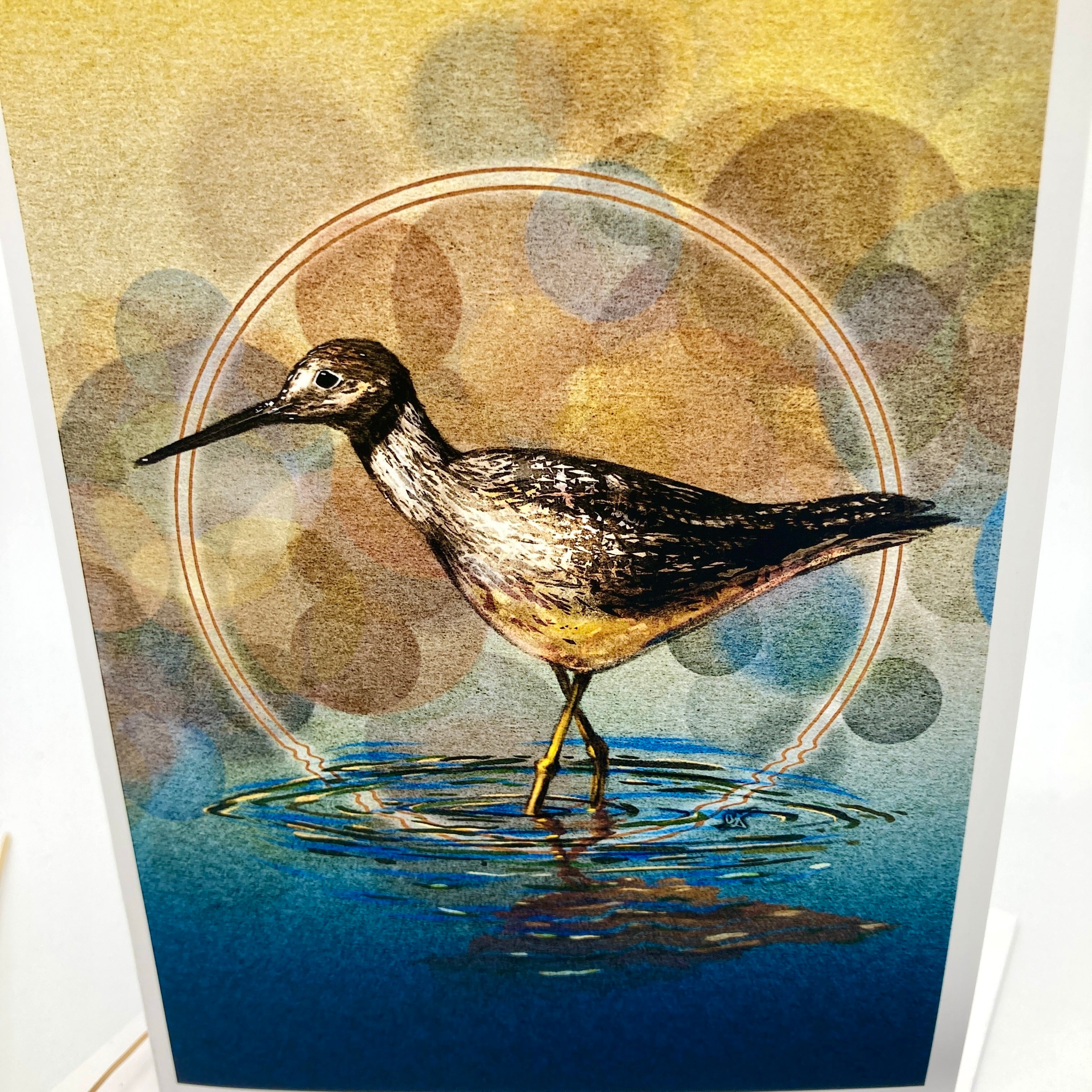 A square art print featuring a detailed illustration of a wading bird standing in blue water, with a circular halo and warm golden bokeh background.