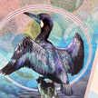 A close-up of a colorful art print or card featuring a detailed illustration of a cormorant with wings spread, set against an abstract circular background in shades of blue, teal, pink, and purple.