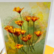A close up of a stylized floral greeting card showing a cluster of orange poppy-like flowers with green stems on a textured pale green background with soft yellow bokeh circles and a faint circular line motif. 