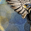 Artistic illustration of a falcon with outstretched wings against a watercolor background