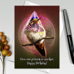 Greeting card with a hummingbird wearing a party hat on a branch, surrounded by decorative elements.