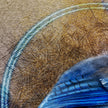 Close-up of a blue feather on a textured brown surface