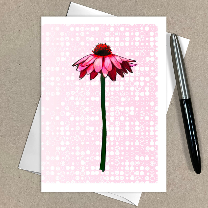 Greeting card with a pink flower illustration on a polka dot background, pen to the side.