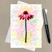 Greeting card with pink flower design on a patterned background, accompanied by a pen.