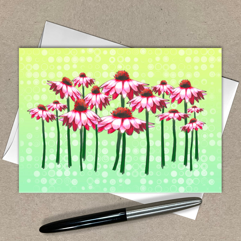 Greeting card with pink flowers on a green background, pen and envelope on a beige surface