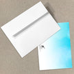 White envelope and blue gradient card on a beige surface