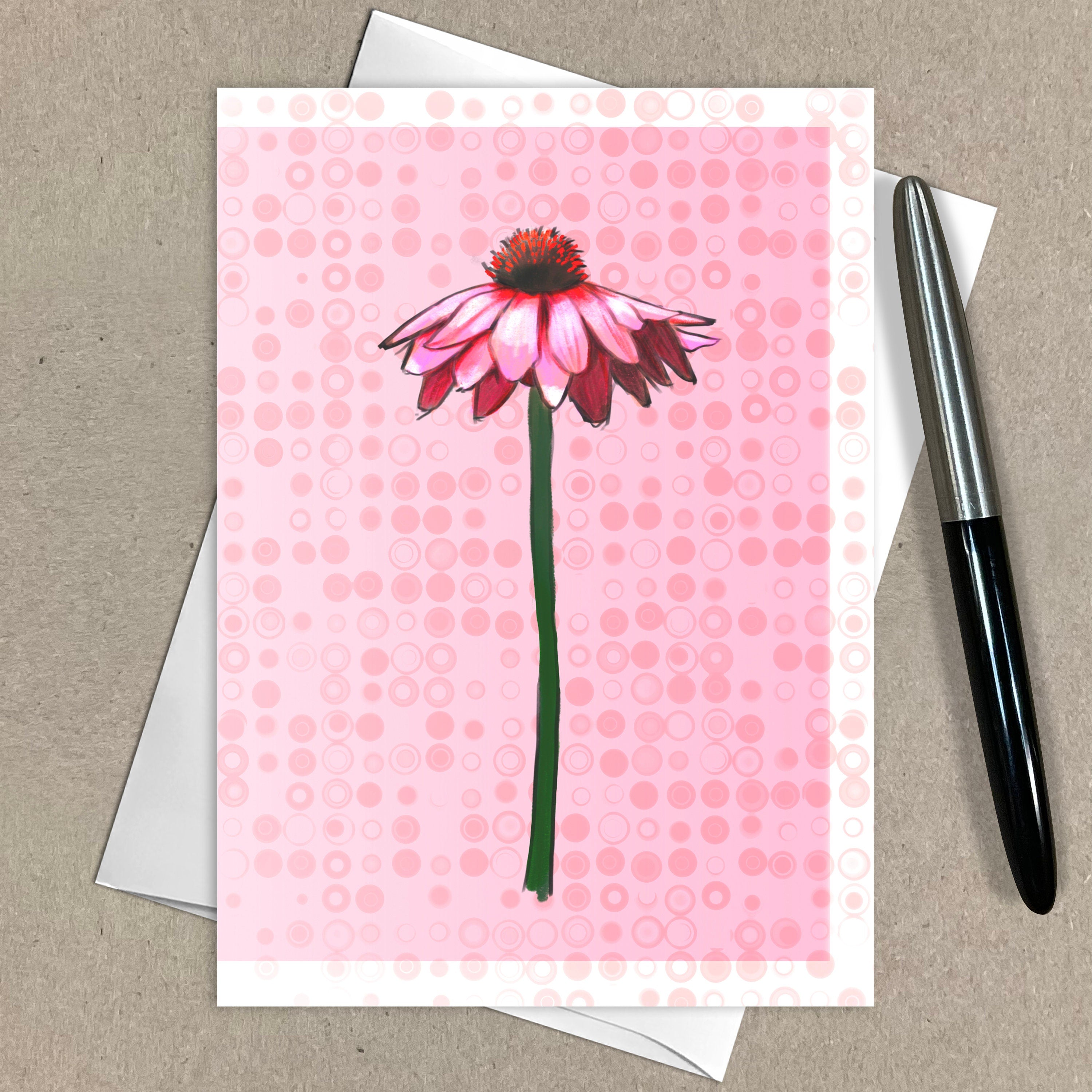 Greeting card with pink flower design on a pink polka dot background, pen on the side.